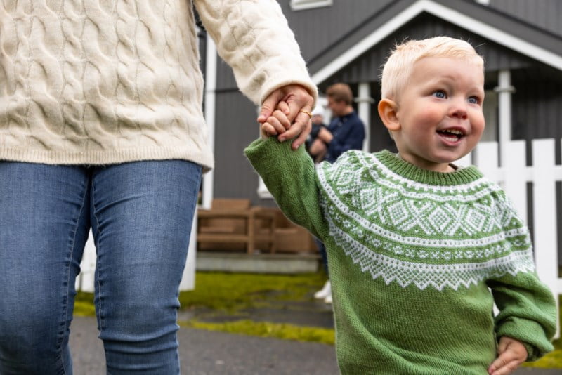 Blid gut med grøn genser som held mammaen sin i handa