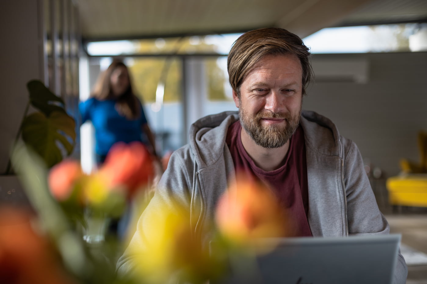 Mann framfor pc med dame i bakgrunnen